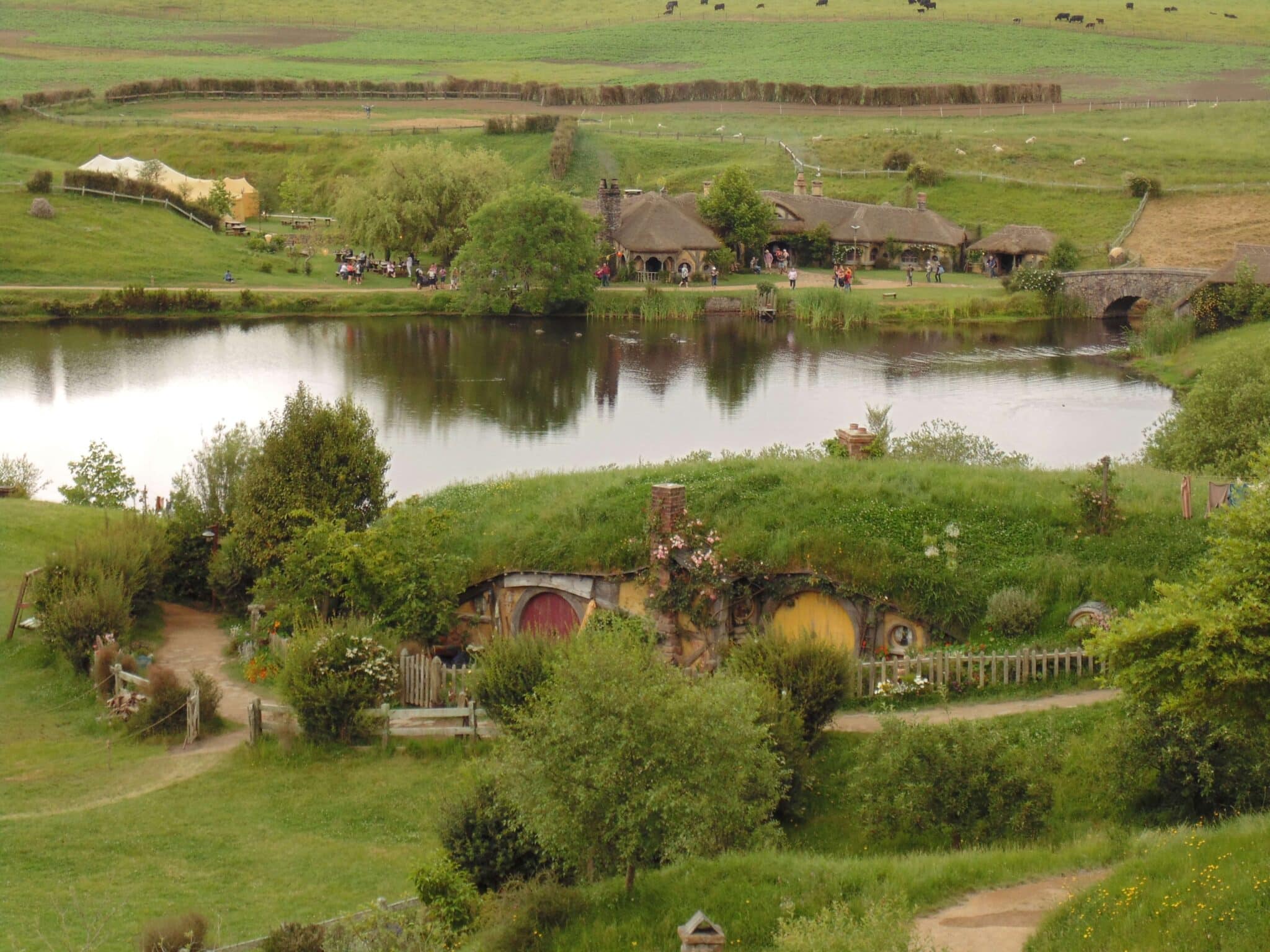 Hobbit-Haus mit runden Türen und begrüntem Dach in einer ländlichen Umgebung.