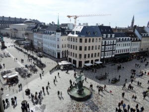 Blick auf einen Platz in Kopenhagen mit einem Brunnen und mehreren historischen Gebäuden.