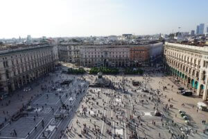 Blick auf die Piazza del Duomo in Mailand mit Menschen und Gebäuden im Hintergrund.
