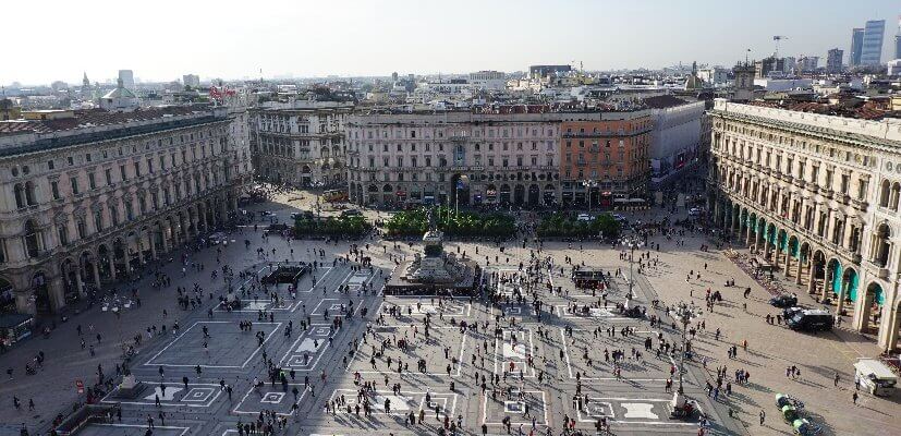 Blick auf die Piazza del Duomo in Mailand mit Menschen und Gebäuden im Hintergrund.
