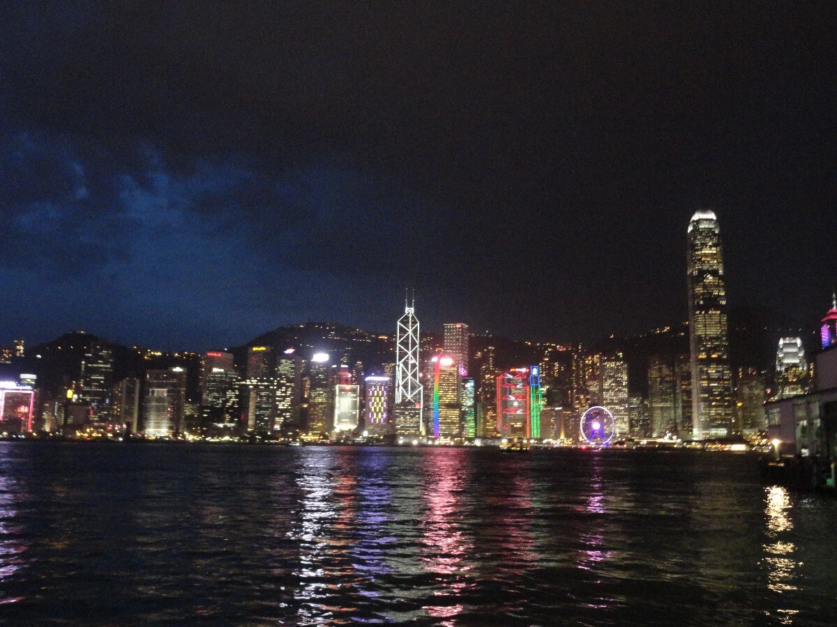 Nachtansicht der Hongkonger Skyline mit beleuchteten Wolkenkratzern und Wasserreflexionen.