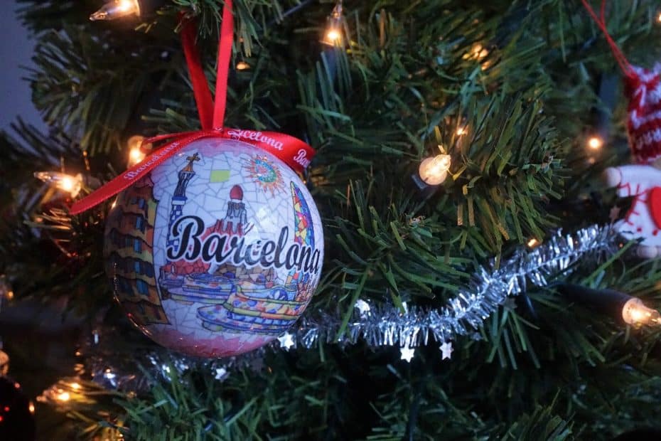 Weihnachtsbaumkugel mit einem bunten Barcelona-Motiv und rotem Band zum Aufhängen.