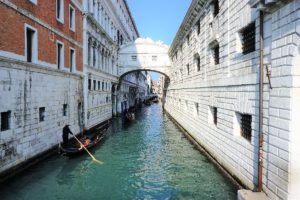 Ein Kanal in Venedig mit der Seufzerbrücke und einem Gondoliere, der auf dem Wasser paddelt.