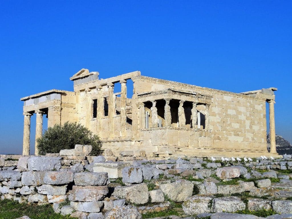 Das Erechtheion, ein antiker Tempel auf der Akropolis in Athen, mit Säulen und Steinen im Vordergrund.