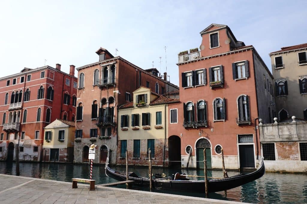 Reihen von historischen Gebäuden am Kanal in Venedig mit Wasser und einem Boot im Vordergrund.