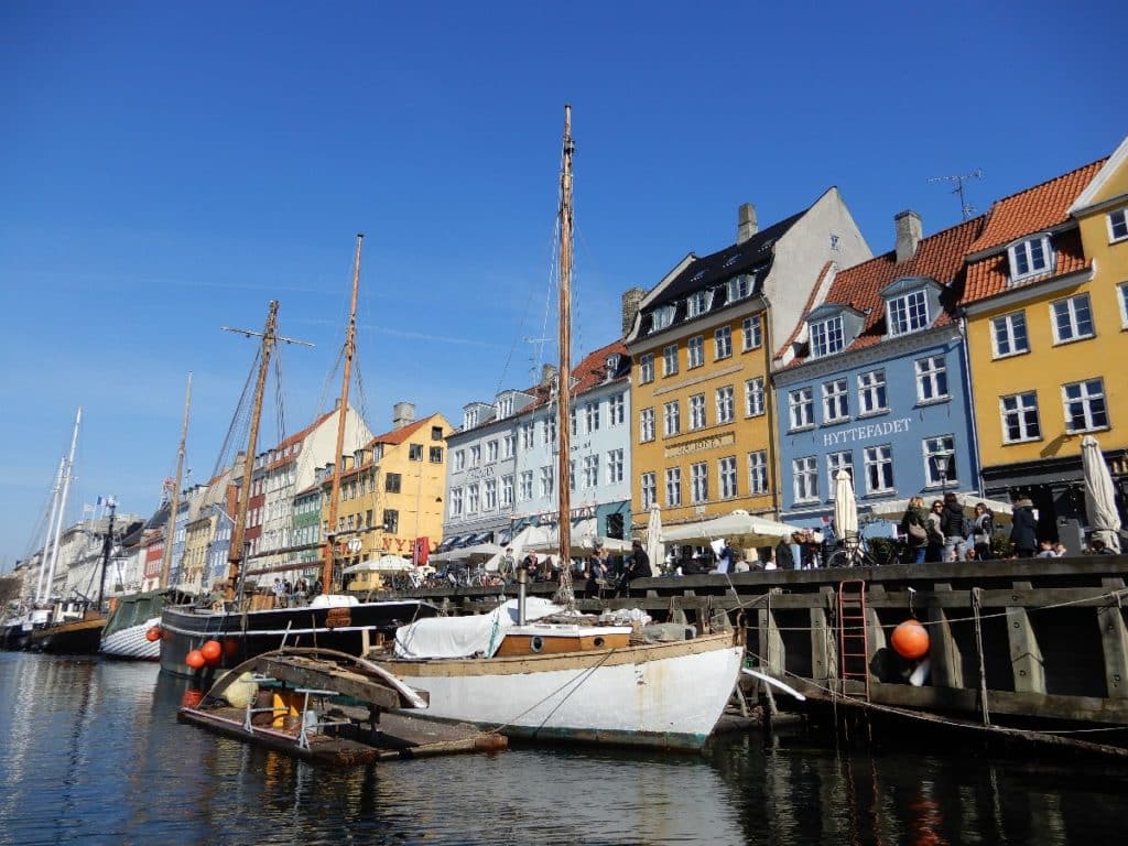 Bunte Häuser entlang eines Hafens in Kopenhagen mit Booten im Vordergrund.