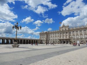 Der Königliche Palast von Madrid mit einer Gruppe von Menschen im Vordergrund und einer Laterne auf dem Platz.