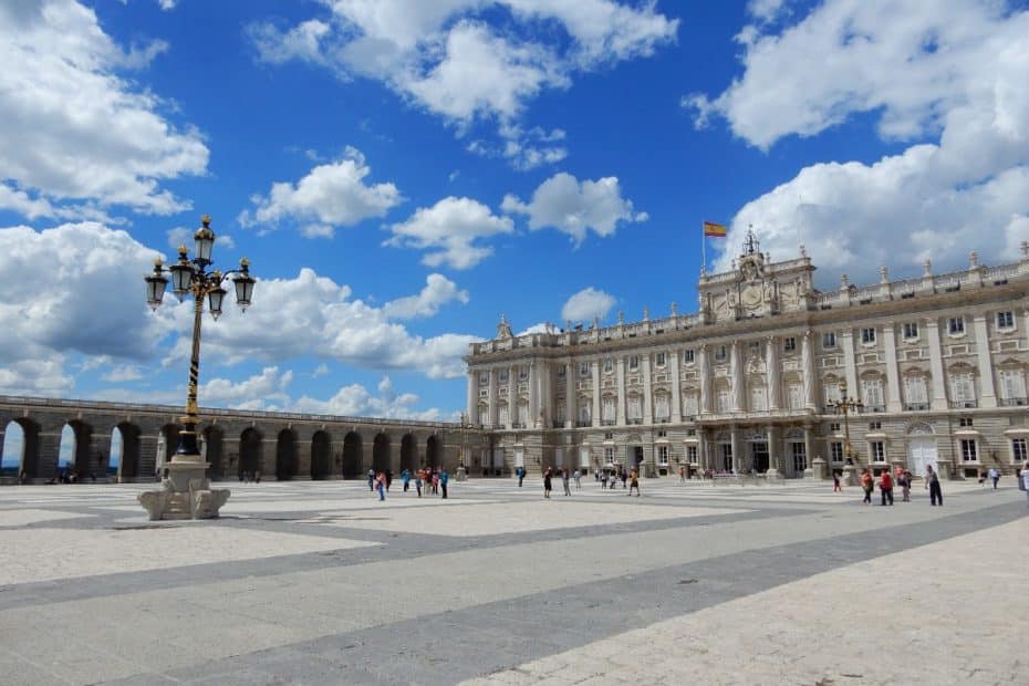 Der Königliche Palast von Madrid mit einer Gruppe von Menschen im Vordergrund und einer Laterne auf dem Platz.