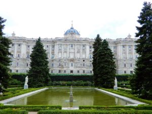 Der Königliche Palast von Madrid mit einem Garten und einem Wasserbecken im Vordergrund.