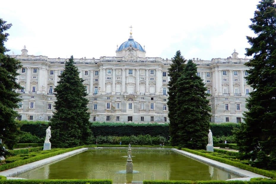Der Königliche Palast von Madrid mit einem Garten und einem Wasserbecken im Vordergrund.