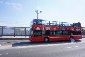 Roter Doppeldeckerbus mit Werbung für die Valencia Tour auf einer Straße.