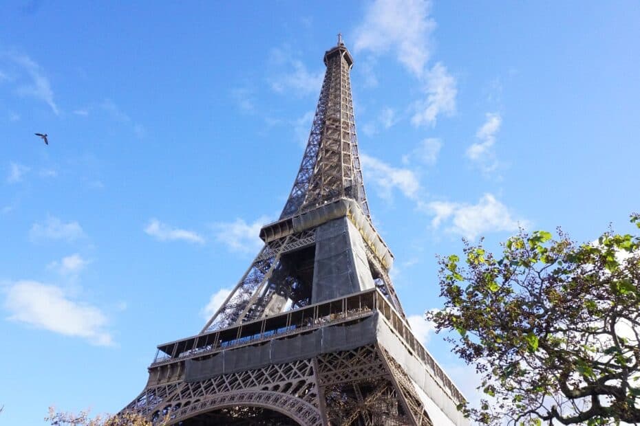 Eiffelturm in Paris mit Gerüst während Renovierungsarbeiten unter blauem Himmel.