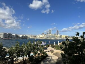 Blick auf die Stadt Valletta mit modernen Gebäuden und dem Hafen im Vordergrund.
