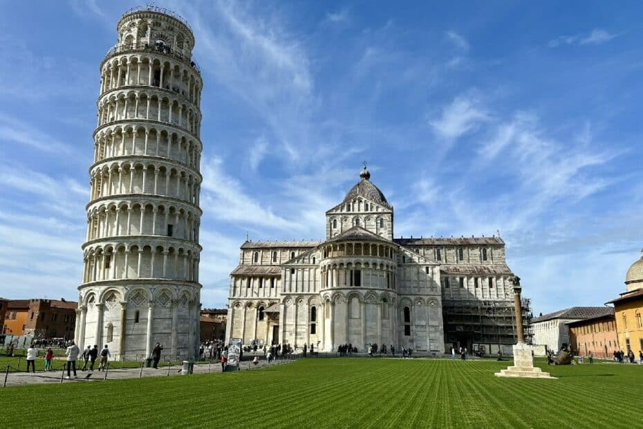 Der Schiefe Turm von Pisa neben der Kathedrale von Pisa unter blauem Himmel.