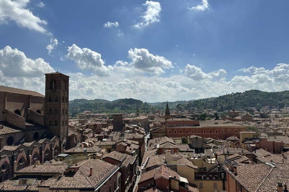 Blick auf eine Stadt mit roten Dächern und historischen Gebäuden unter einem blauen Himmel mit Wolken.