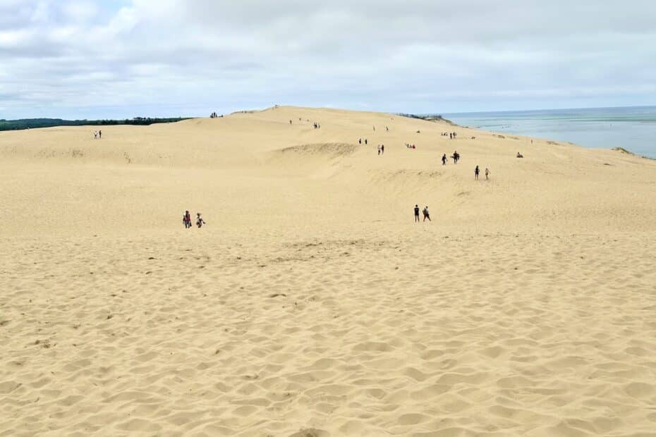 Sanddüne mit mehreren Personen, die sich auf der Oberfläche bewegen und die Landschaft erkunden.