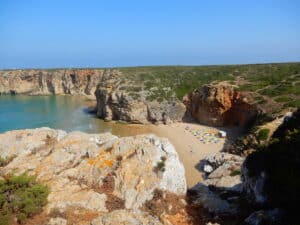 Blick auf eine Küstenlandschaft mit einem kleinen Strand und Klippen im Hintergrund.