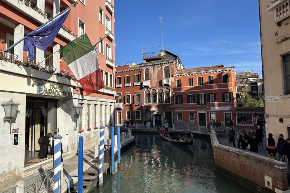 Kanal in Venedig mit Gebäuden und italienischer Flagge im Vordergrund.