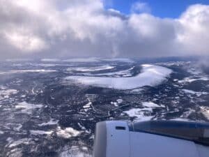 Luftaufnahme einer schneebedeckten Landschaft mit Bergen und Wolken.