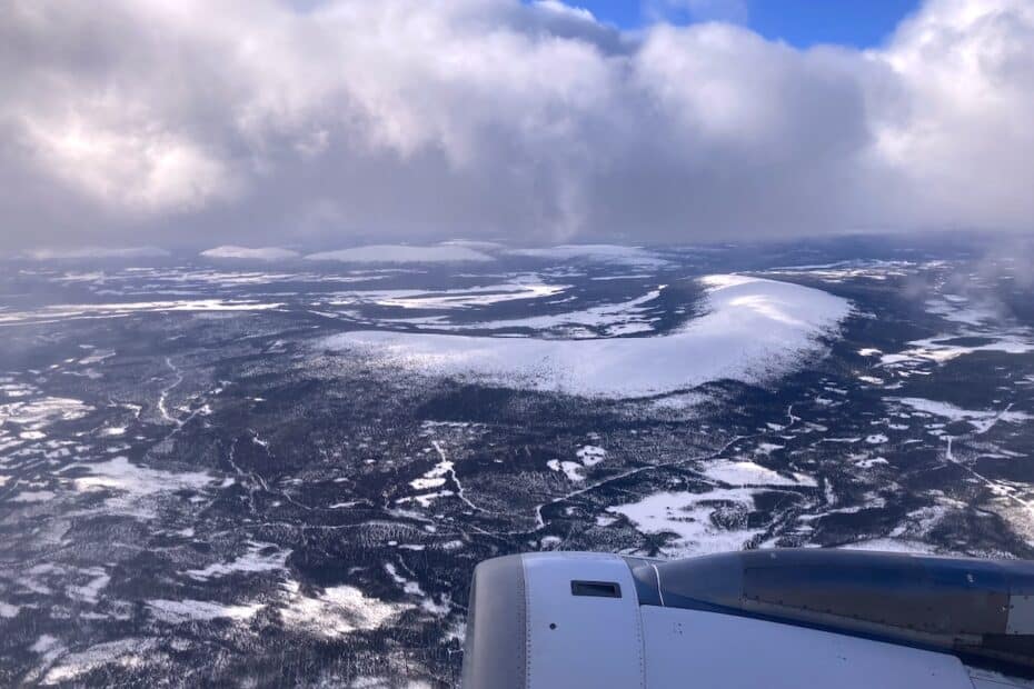 Luftaufnahme einer schneebedeckten Landschaft mit Bergen und Wolken.