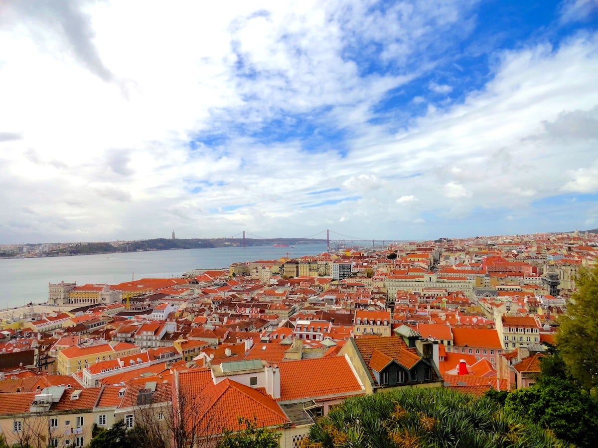 Panoramaansicht von Lissabon mit roten Dächern und blauem Himmel mit Wolken.
