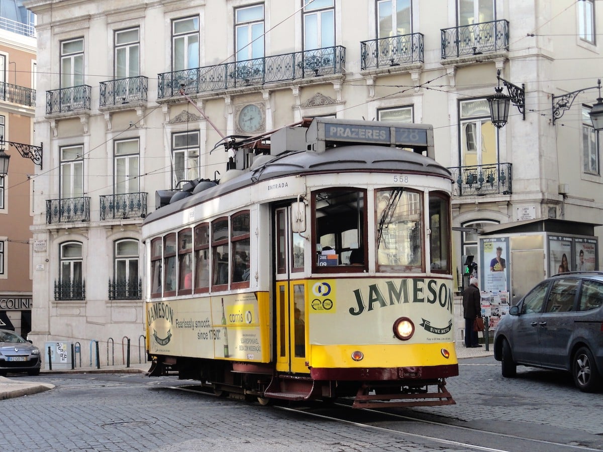 Eine Straßenbahn in Lissabon mit einer Jameson-Werbung auf der Seite, die auf einer Straße fährt.