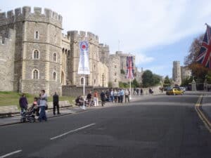 Windsor Castle mit Menschen, die auf der Straße stehen, und Union Jack-Flaggen im Vordergrund.