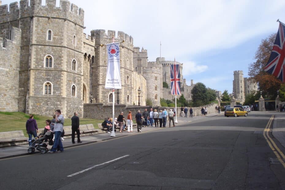 Windsor Castle mit Menschen, die auf der Straße stehen, und Union Jack-Flaggen im Vordergrund.