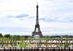 Eiffelturm in Paris, sichtbar vor einer grünen Landschaft und einem klaren Himmel.