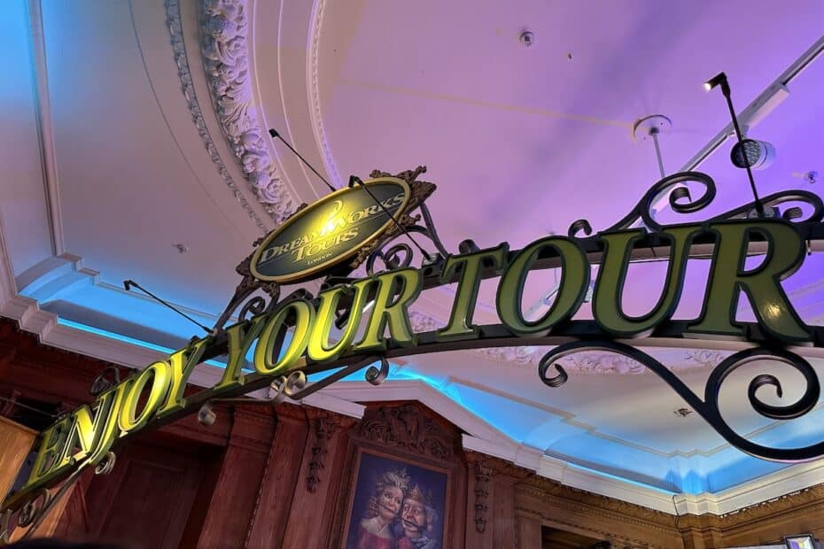 Ein dekoratives Schild mit der Aufschrift 'Enjoy Your Tour' in einem Innenraum mit buntem Licht.