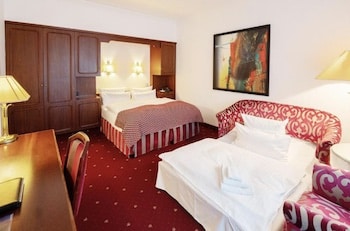 Hotelzimmer mit einem Doppelbett, einem Schlafsofa und einem Schreibtisch in einem modernen Design.