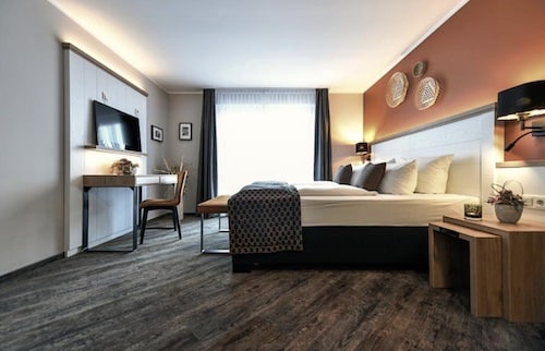 Ein Hotelzimmer mit einem Doppelbett, einem Schreibtisch und einem Holzregal an der Wand.