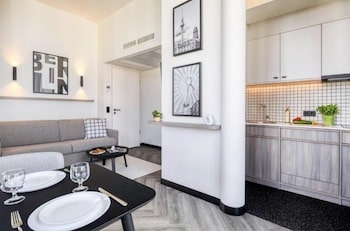 Moderne Wohnküche mit einem grauen Sofa, einem Esstisch und einer Küchenzeile in einem Berliner Apartment.