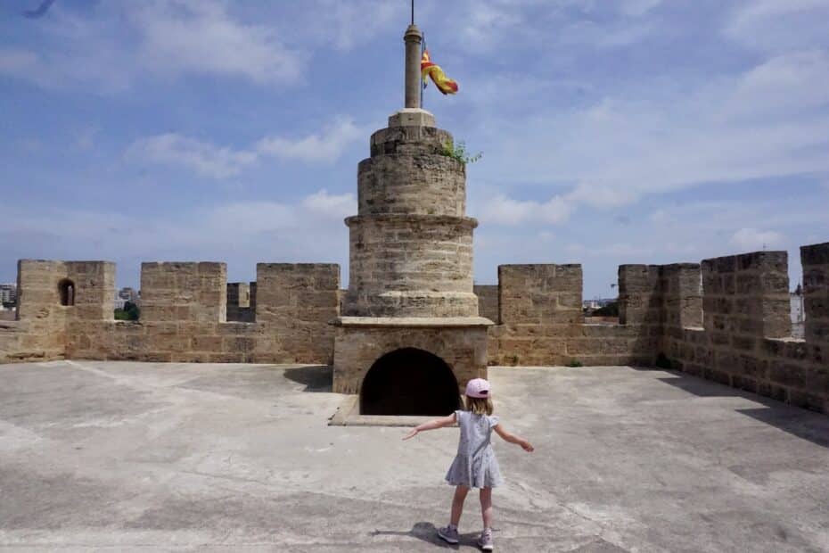 Ein Mädchen in einem Kleid steht auf einer Festung mit einer Fahne auf dem Turm.