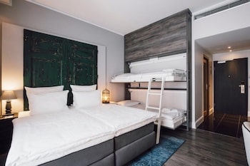Hotelzimmer mit einem Doppelbett und einem Etagenbett an der Wand montiert.