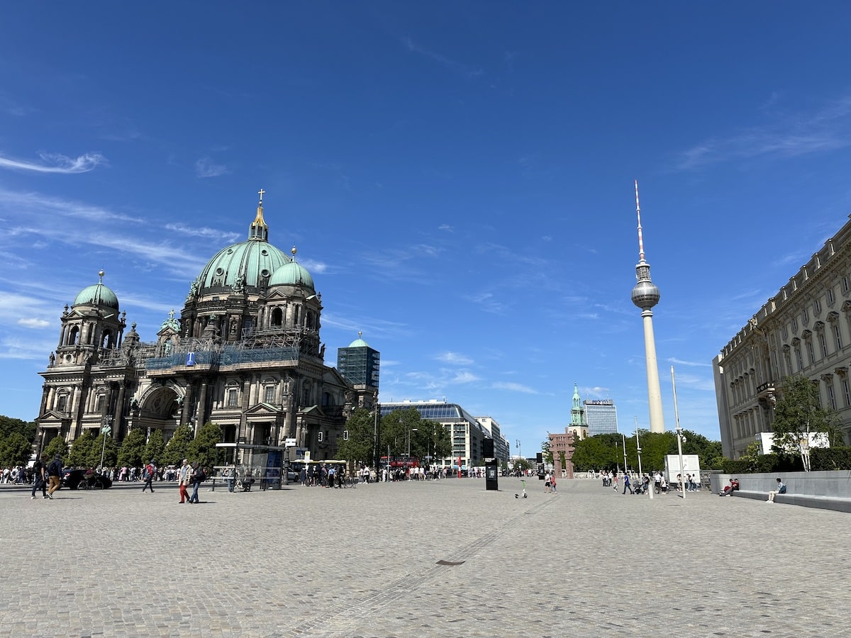 Berliner Dom mit grüner Kuppel und Fernsehturm im Hintergrund auf einem Platz in Berlin.