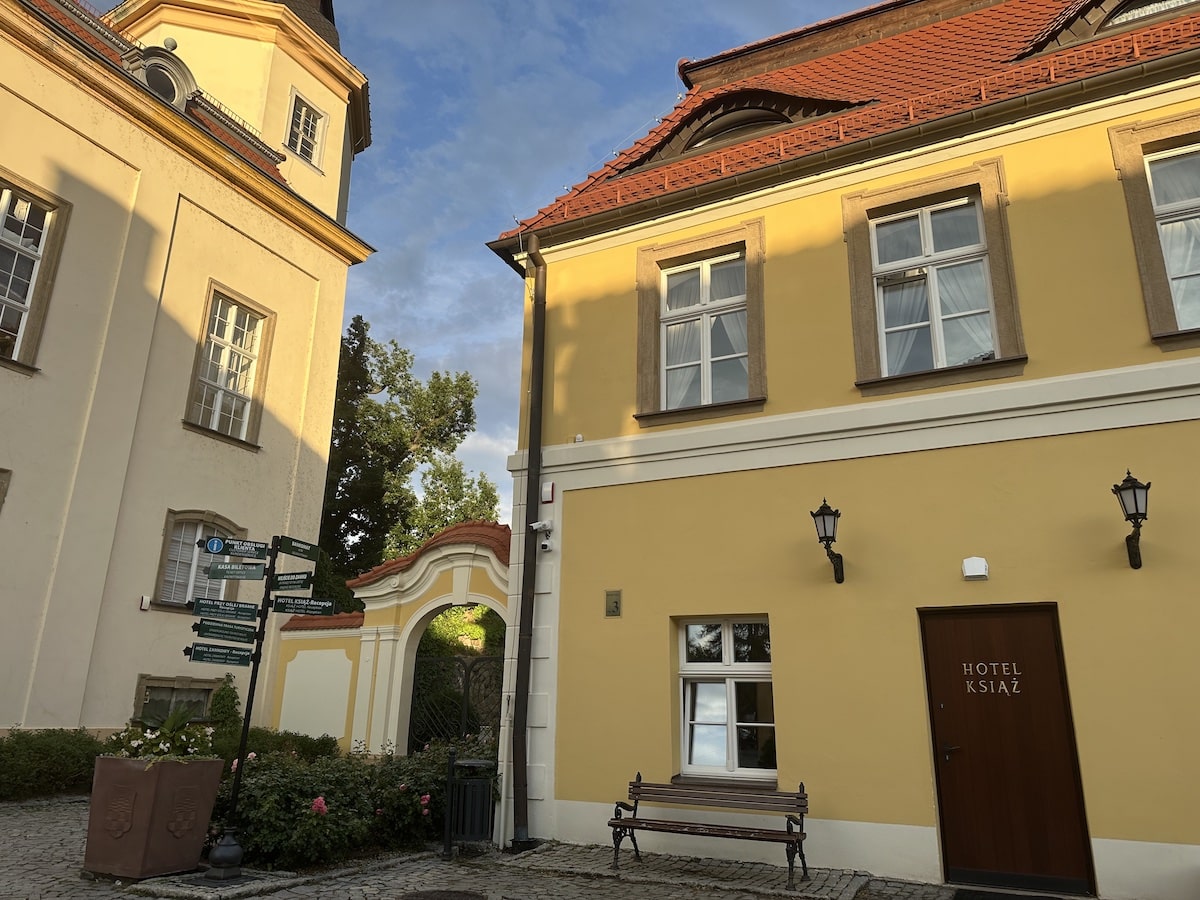Gebäude mit gelber Fassade und Hotel Książ Eingangstür in einer ruhigen Umgebung.