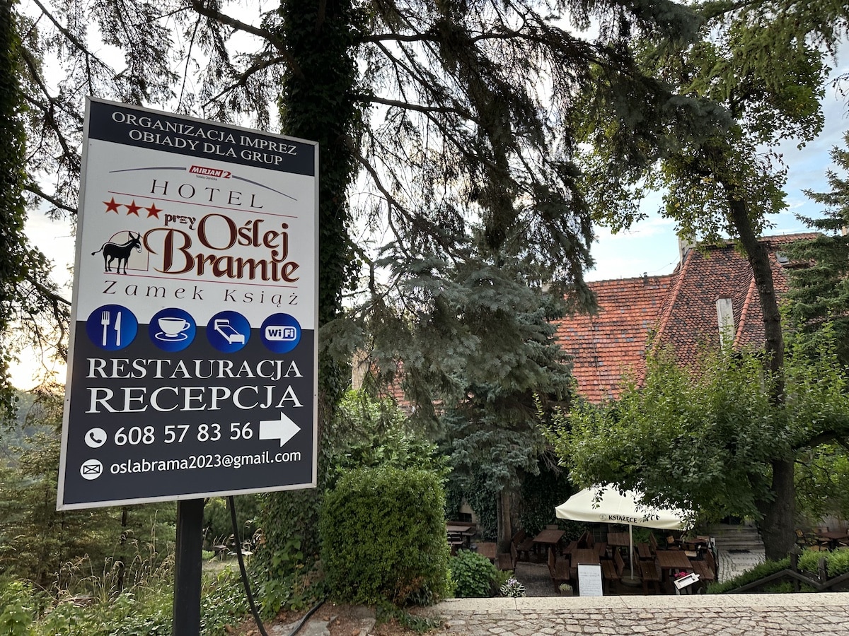 Schild des Hotels Oslej Bramie mit Informationen zu Restaurant und Empfang in der Nähe eines Gebäudes.