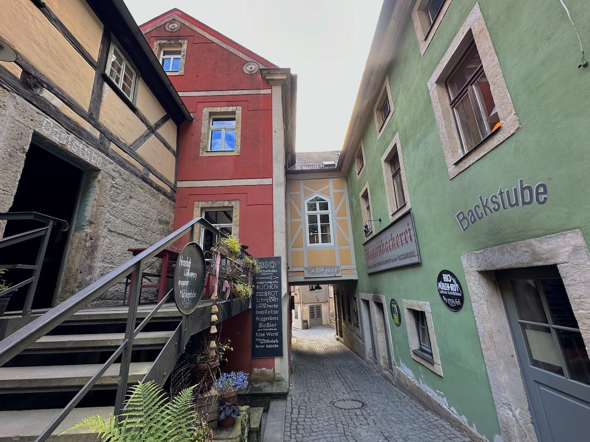 Enge Gasse mit historischen Gebäuden in verschiedenen Farben und einem überdachten Durchgang.