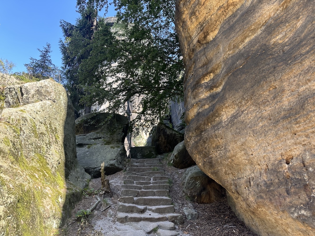 Steinerne Treppe, die zwischen großen Felsen in einem Wald führt.