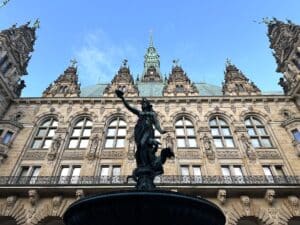 Brunnen mit einer Statue einer Frau, die eine Fackel hält, vor dem Hamburger Rathaus.