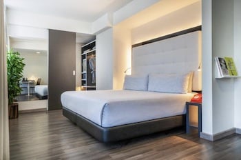 Ein modernes Hotelzimmer mit einem Doppelbett, Schrank und Tisch im Hintergrund.