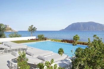 Ein Pool mit Liegen und Blick auf das Meer und die umliegenden Berge.