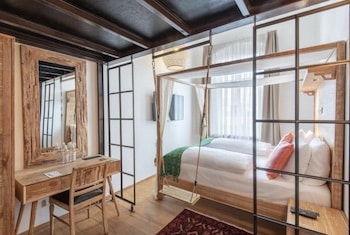Ein modernes Hotelzimmer mit einem Bett, einem Schreibtisch und einem Spiegel aus Holz und Glas.