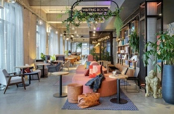 Wartebereich mit modernen Möbeln und Pflanzen im Moxy Berlin Ostbahnhof.