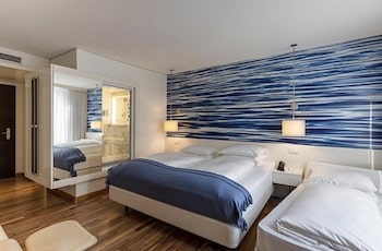Hotelzimmer mit zwei Betten, einem Spiegel und einer blauen Wand mit Wellenmuster.
