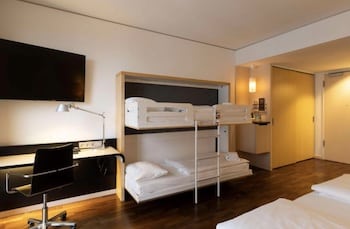 Hotelzimmer mit einem Etagenbett, einem Schreibtisch und einem Fernseher an der Wand.
