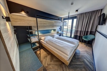 Ein Hotelzimmer mit einem Doppelbett, modernen Möbeln und großen Fenstern.