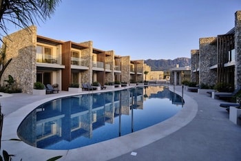 Moderne Hotelanlage mit einem geschwungenen Pool und Steinfassaden in der Architektur.