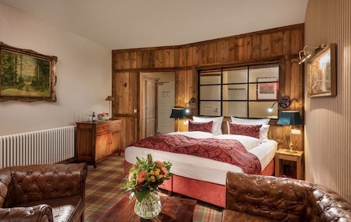 Hotelzimmer mit einem Doppelbett, einem Sitzbereich und Holzverkleidung an den Wänden.